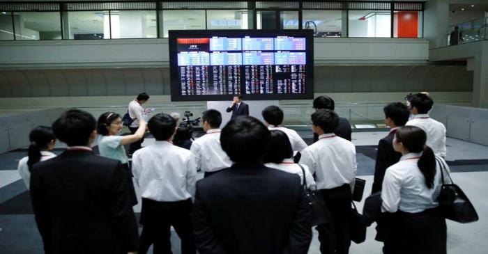 Visitors look at an electronic stock quotation board at the TSE in Tokyo