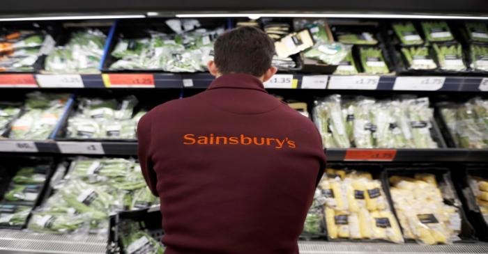 A Sainsbury's worker stacks a vegetable shelf in a store in Redhill