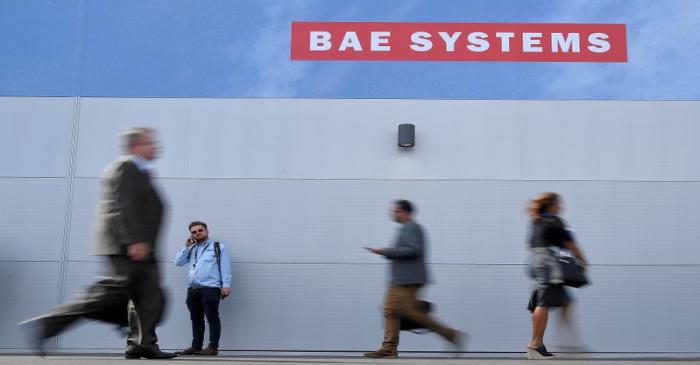Trade visitors walk past an advertisement for BAE Systems at Farnborough International Airshow
