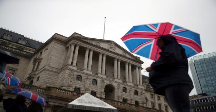 FILE PHOTO: A pedestrian shelters under an umbrella in front of the Bank of England, in London