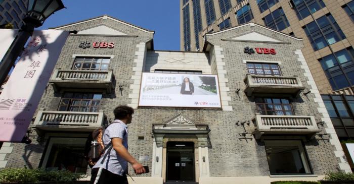 FILE PHOTO: Man walks past a building of Swiss bank UBS in Shanghai