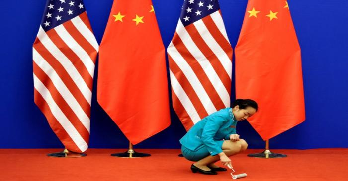 FILE PHOTO: An attendent cleans the carpet next to U.S. and Chinese national flags in Beijing