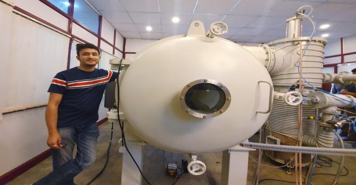 Bellatrix Aerospace CEO Rohan Ganapathy stands next to a vacuum chamber at their laboratory in