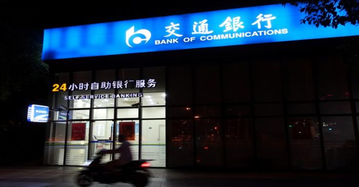 FILE PHOTO:  Man rides past a Bank of Communications branch in Shanghai