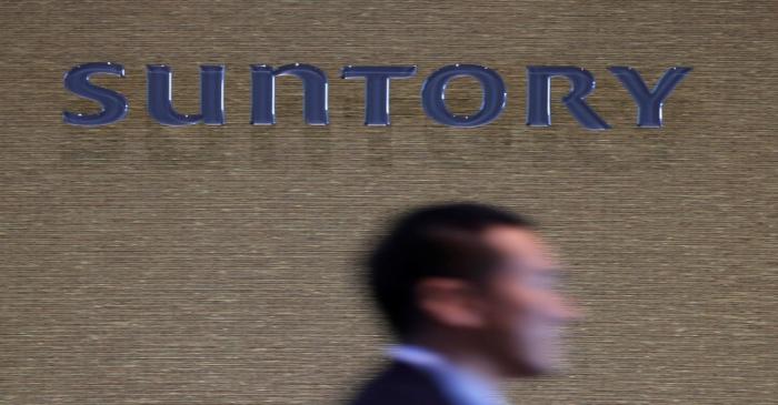 FILE PHOTO: Man walks past a signboard of Suntory Holdings at the entrance of Suntory World