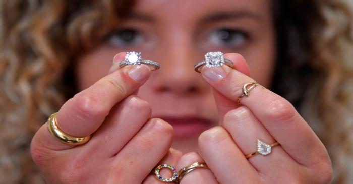 Sophie Lomax, Head of Design, holds two diamond rings designed and made at 77 Diamonds in