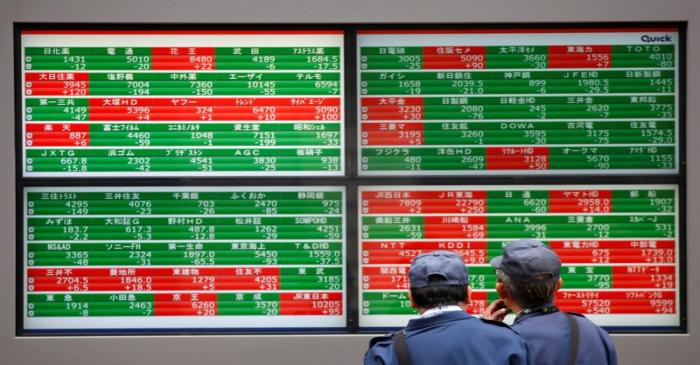 Men look at stock quotation boards outside a brokerage in Tokyo