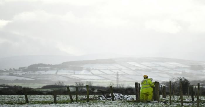 Snow covers the hills as farm workers mend fences near Londonderry