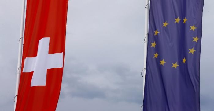 FILE PHOTO: Flags of the European Union and Switzerland flutter in the wind in Blotzheim