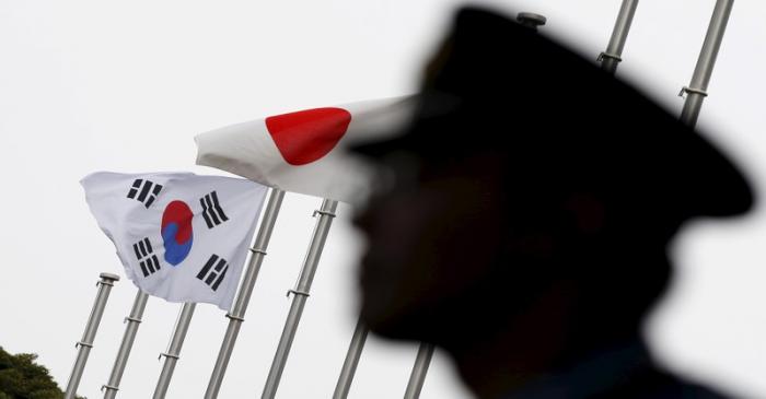 Police officer stands guard near Japan and South Korea national flags at hotel, where South