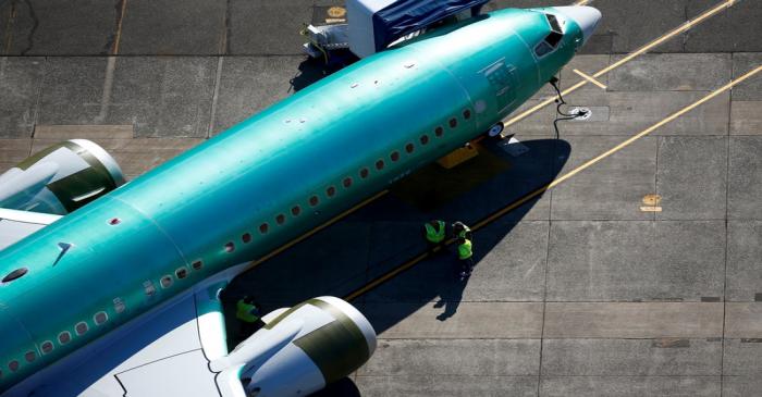 Workers gather next to an unpainted Boeing 737 MAX aircraft seen parked at Renton Municipal