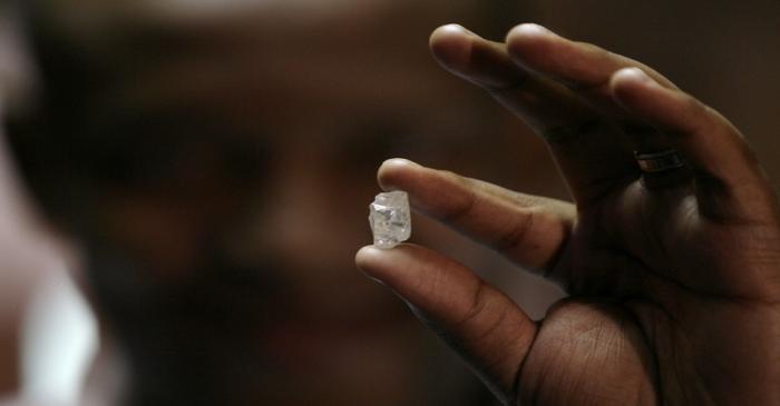 A visitor holds a 17 carat diamond at a Petra Diamonds mine in Cullinan