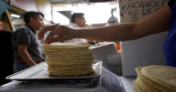 FILE PHOTO: An employee weighs a stack of freshly made corn tortillas at a tortilla factory in