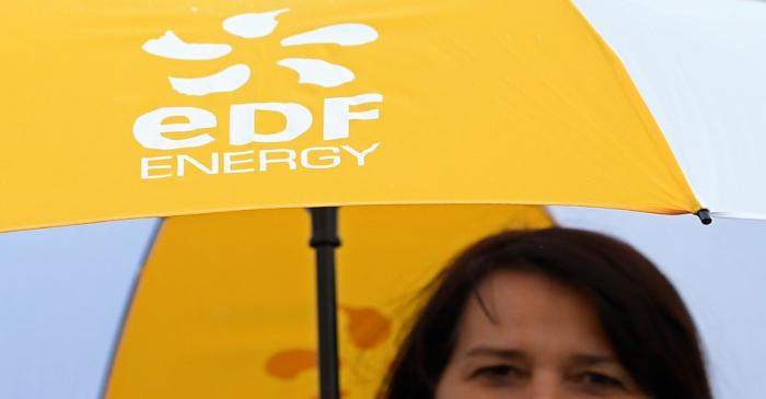An employee carries an umbrella with the EDF energy logo near the Hinkley Point C nuclear power