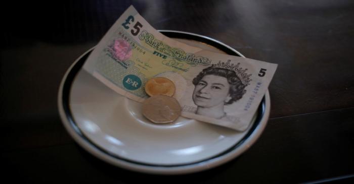 An English five Pound note and coins are seen at a restaurant in the British overseas territory
