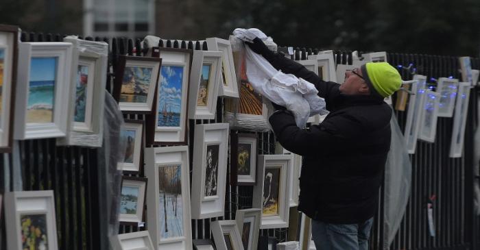FILE PHOTO: A street vendor dries rain off artworks he is selling on the streets in Dublin