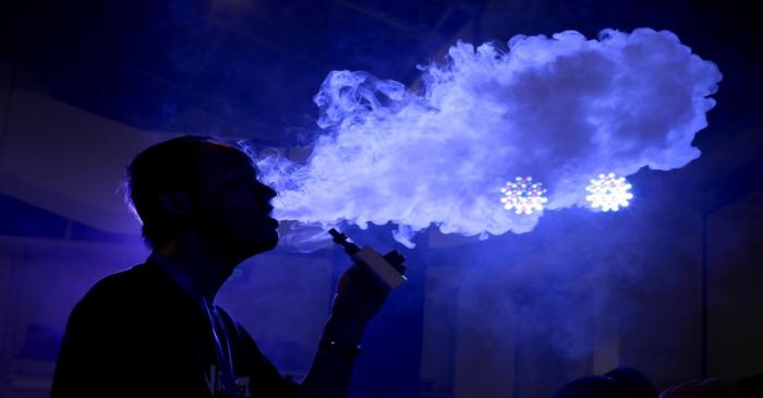 FILE PHOTO: An exhibitor staff member uses an electronic cigarette at the Beijing International