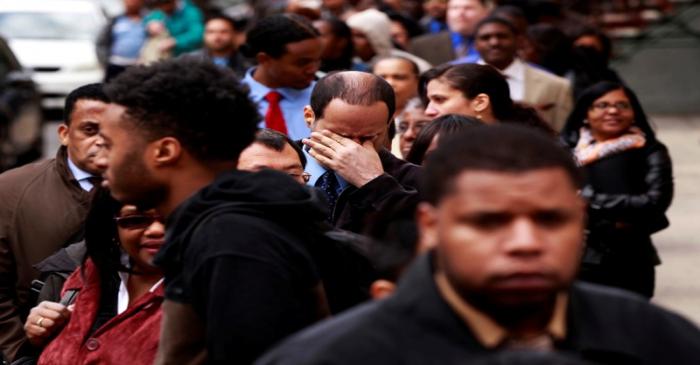 FILE PHOTO: FILE PHOTO: Man rubs his eyes as he waits in a line of jobseekers, to attend the