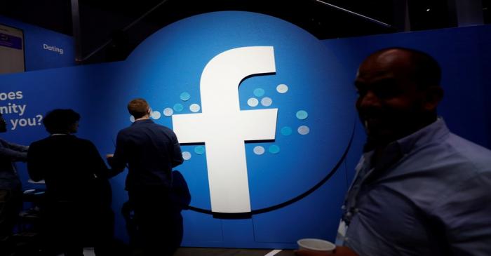 FILE PHOTO: Attendees walk past a Facebook logo during Facebook Inc's F8 developers conference