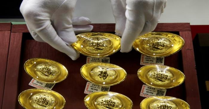 FILE PHOTO: A sales assistant places gold ornaments at Caibai Jewelry store in Beijing