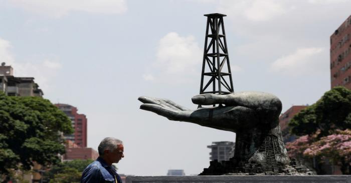 FILE PHOTO: A man walks past a sculpture outside a building of Venezuela's state oil company
