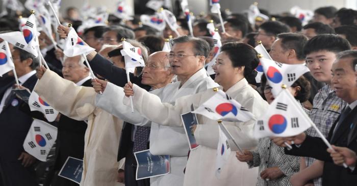 South Korean President Moon Jae-in and his wife Kim Jung-sook wave the national flags during a