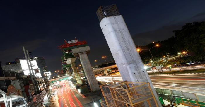 Cars pass Skytrain construction site in Bangkok