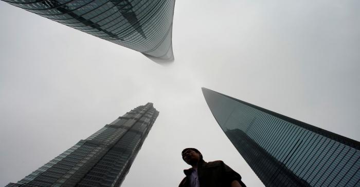 Man walks by skyscrapers at Lujiazui financial district in Shanghai