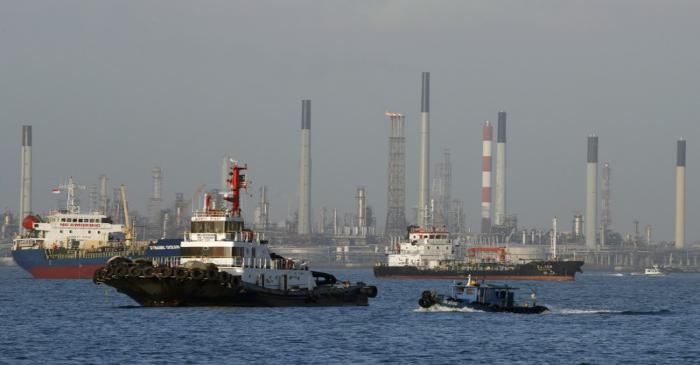 Vessels pass an oil refinery in the waters off the southern coast of Singapore