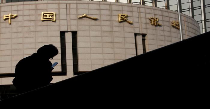 Man sits in front of the headquarters of the People's Bank of China, the central bank, in