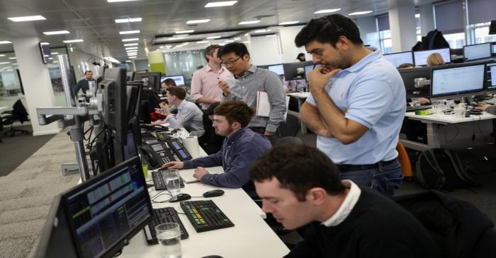 Traders looks at financial information on computer screens on the IG Index trading floor