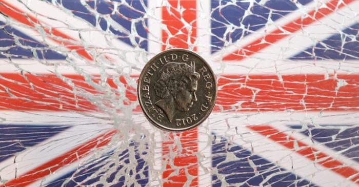 A pound coin is placed on broken glass and British flag in this illustration picture
