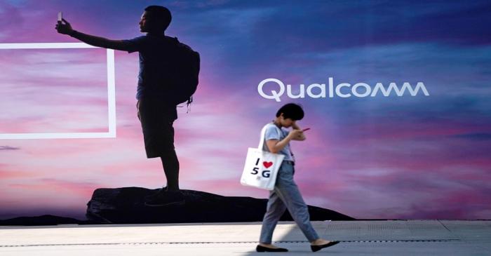 A woman walks past a sign advertising Qualcomm at Mobile World Congress (MWC) in Shanghai