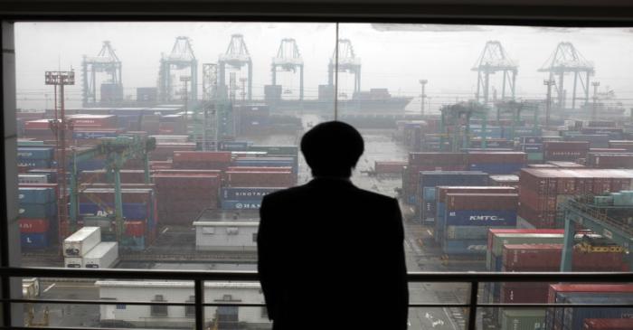 An employee views the Port of Shanghai from an office window