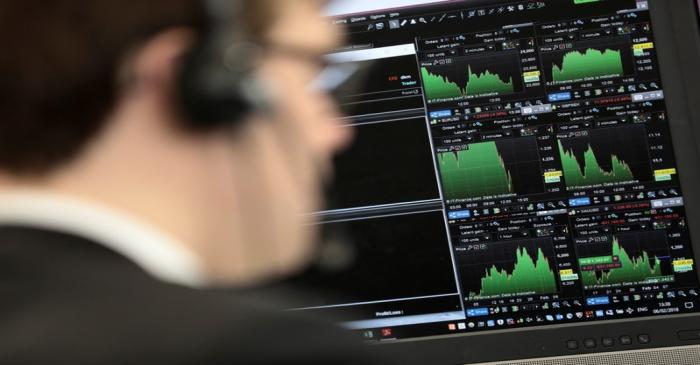 A broker looks at financial information on computer screens on the IG Index the trading floor