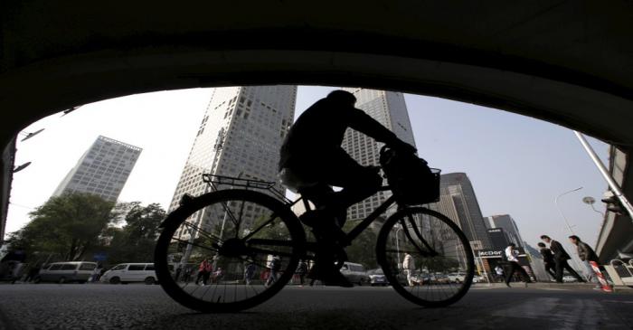 FILE PHOTO: A man rides his bicycle across the street under the Guomao bridge at the Central