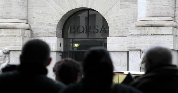 People look at Milan's stock exchange building in downtown Milan