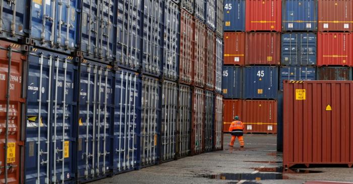 FILE PHOTO: A dock worker walks between empty shipping containers at Peel Ports Liverpool