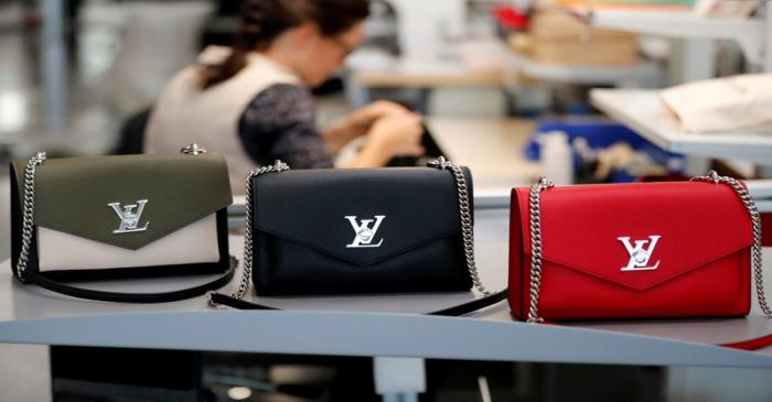 FILE PHOTO: Louis Vuitton handbags are displayed as an employee works in a Vuitton new high-end