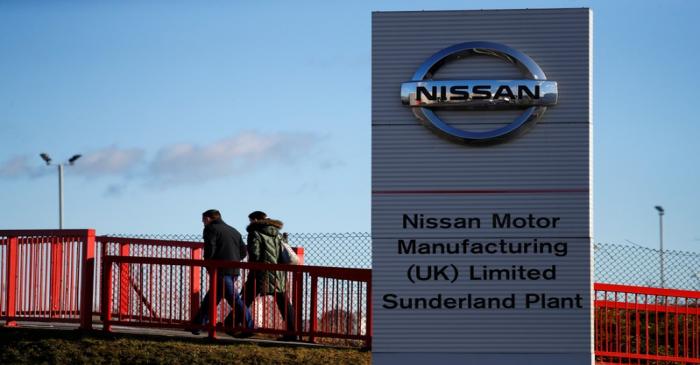 People walk past a sign at the Nissan car plant in Sunderland