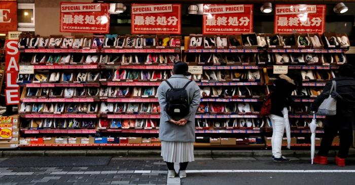 A woman looks at shoes on sale at an outlet store in Tokyo's shopping district