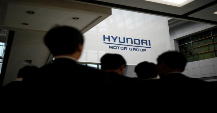 Employees of Hyundai Motor walk past the company's logo after the company's New Year ceremony