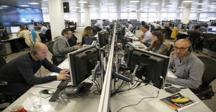 Traders sit at their desks at IG Index in London