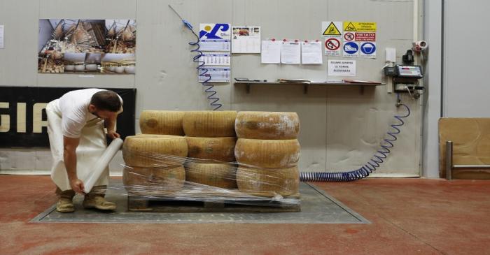 A woorker packages wheel of Parmesan cheese at storehouse shelf 4 Madonne Caseificio
