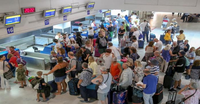 Passengers line up in front of Thomas Cook counters at the airport of Heraklion, on the island
