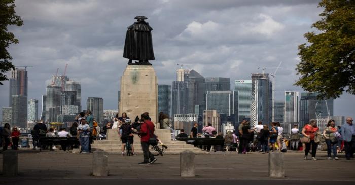 People look out onto the Canary Wharf financial district as they stand at a viewing area in
