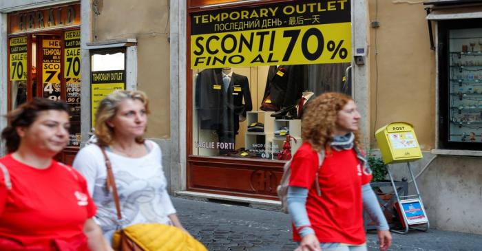 People walk in front of a shop in downtown Rome as Italy's cabinet prepares to approve a 2020