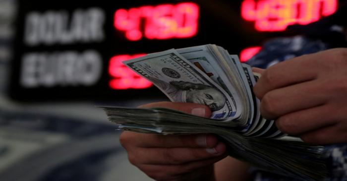 FILE PHOTO: A money changer counts U.S. dollar banknotes at a currency exchange office in
