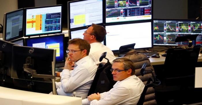 Share traders look at their screens during early afternoon trading on the day of the Brexit
