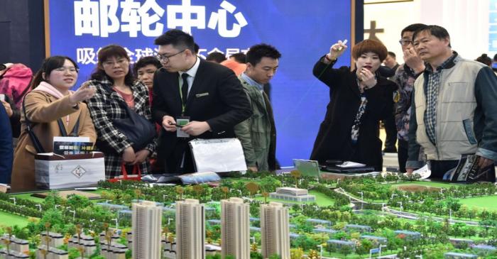 Sales staff introduce models of a residential compound to visitors during Dalian Spring Real